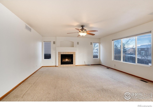 unfurnished living room featuring baseboards, visible vents, ceiling fan, and a tile fireplace