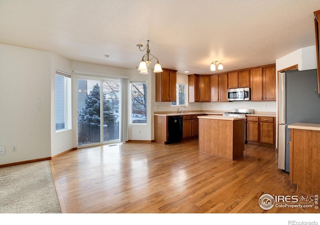 kitchen with a center island, appliances with stainless steel finishes, light countertops, and pendant lighting