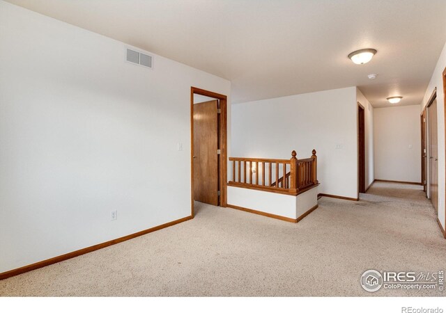 spare room with light carpet, visible vents, and baseboards