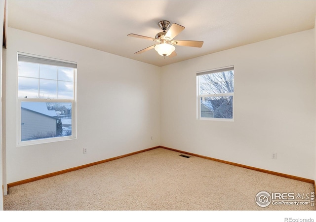 carpeted empty room featuring baseboards, visible vents, and a ceiling fan