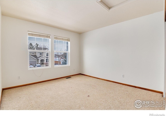 carpeted spare room featuring baseboards and visible vents