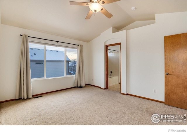 empty room featuring carpet, visible vents, vaulted ceiling, and baseboards