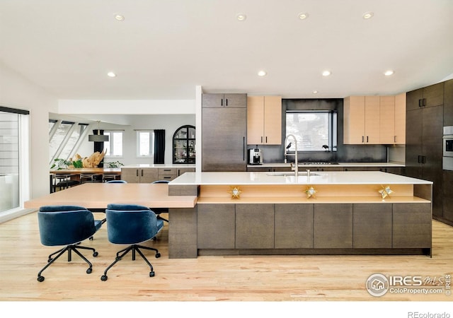 kitchen featuring a sink, light countertops, a large island, and light wood-type flooring