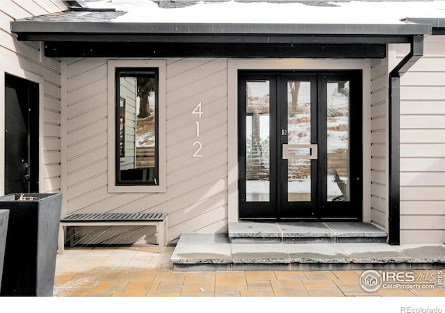 snow covered property entrance with french doors