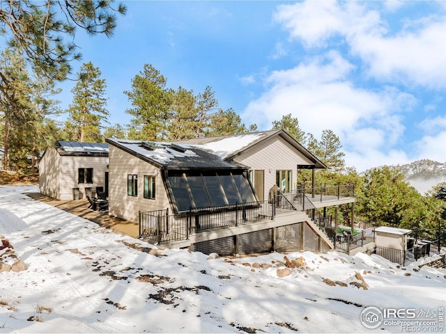 snow covered property with a deck and stairs