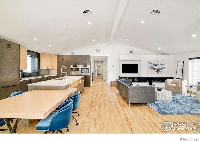 interior space with light wood-style flooring, visible vents, and beamed ceiling