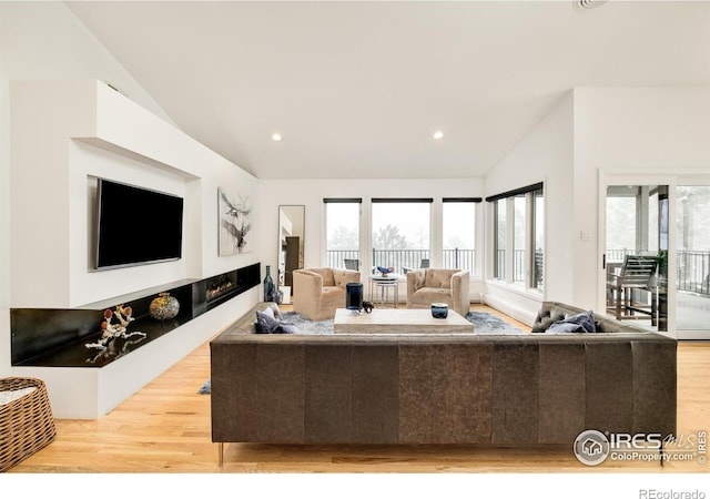 living room featuring lofted ceiling, light wood-style floors, a fireplace, and recessed lighting