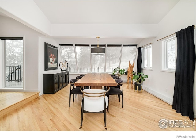 dining room featuring vaulted ceiling, light wood-type flooring, and baseboards