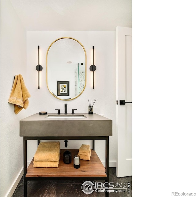 bathroom featuring baseboards and a sink