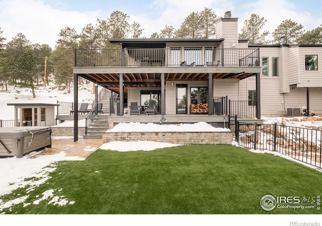 snow covered house with a hot tub, a wooden deck, central AC unit, a chimney, and a yard