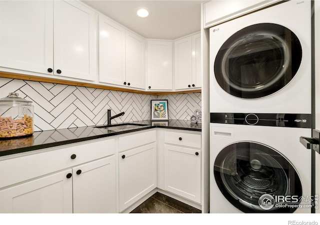 clothes washing area with stacked washer and clothes dryer, a sink, cabinet space, and recessed lighting