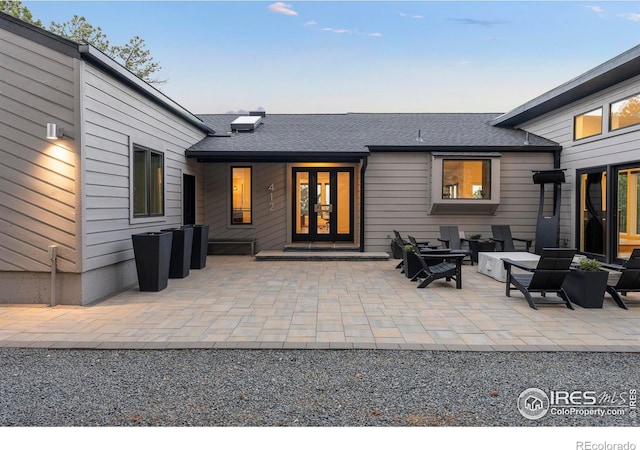 rear view of house with a patio area, french doors, and roof with shingles