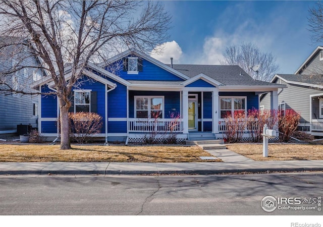 bungalow-style home with a porch, roof with shingles, and central AC unit