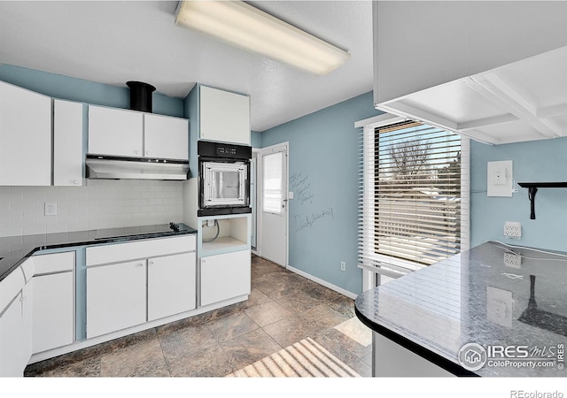 kitchen with wall oven, dark countertops, under cabinet range hood, white cabinetry, and backsplash