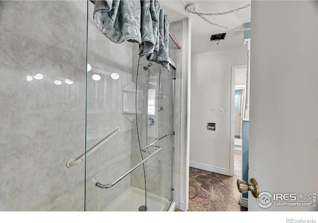 bathroom featuring marble finish floor, a stall shower, and baseboards