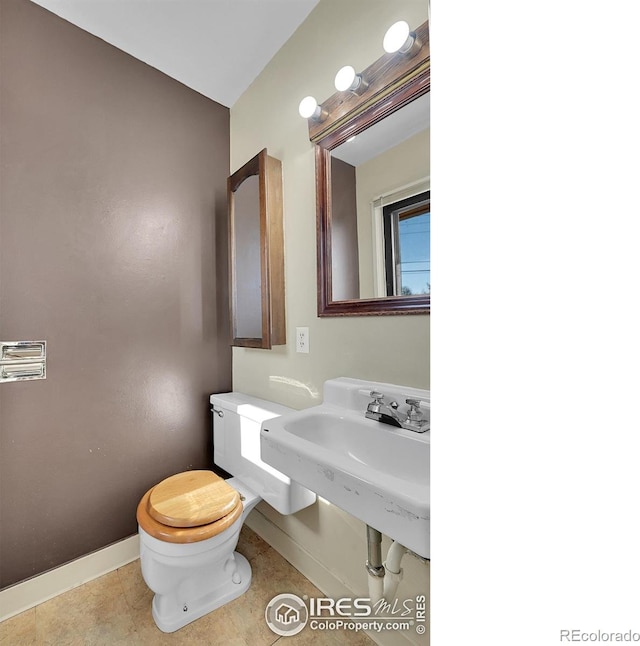 half bath with tile patterned flooring, baseboards, and toilet