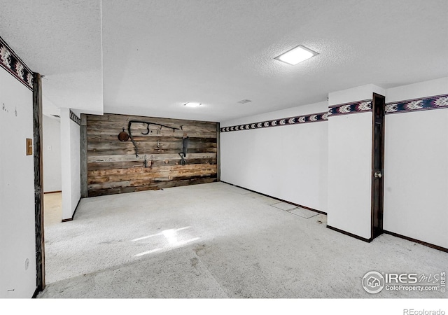 below grade area with wood walls, baseboards, and a textured ceiling