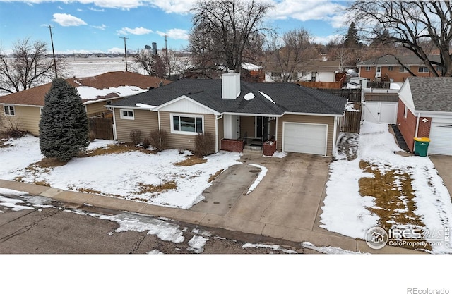 ranch-style house with a garage, concrete driveway, a shingled roof, and fence