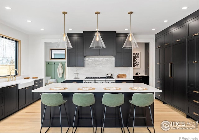 kitchen featuring a breakfast bar, light countertops, light wood-style floors, and a sink