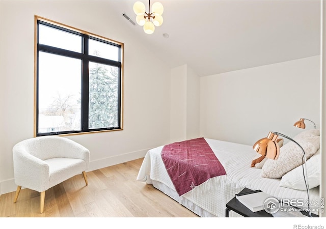 bedroom with visible vents, lofted ceiling, wood finished floors, an inviting chandelier, and baseboards