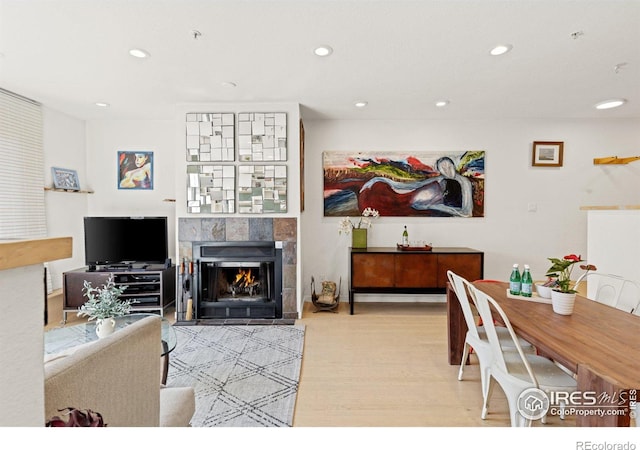 interior space with light wood-style floors, a tiled fireplace, and recessed lighting