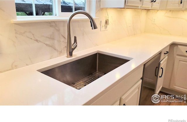 kitchen featuring light countertops, a sink, white cabinetry, and decorative backsplash