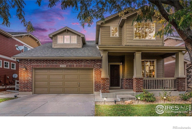 view of front of property featuring a garage, covered porch, brick siding, and driveway