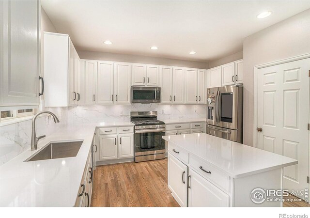 kitchen featuring a sink, stainless steel appliances, light countertops, and white cabinets