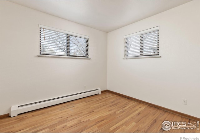 unfurnished room with baseboards, a baseboard radiator, and light wood-style floors