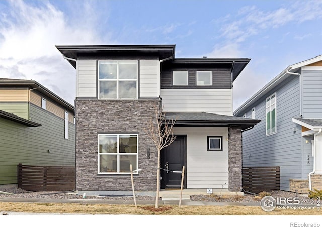 back of property featuring stone siding and fence