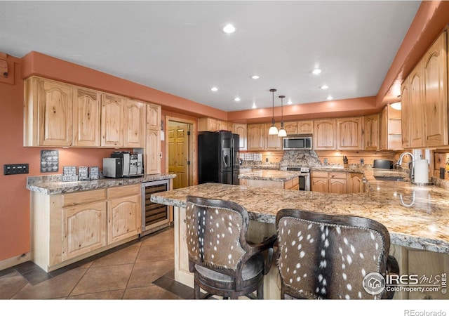 kitchen with wine cooler, appliances with stainless steel finishes, decorative light fixtures, a peninsula, and a sink