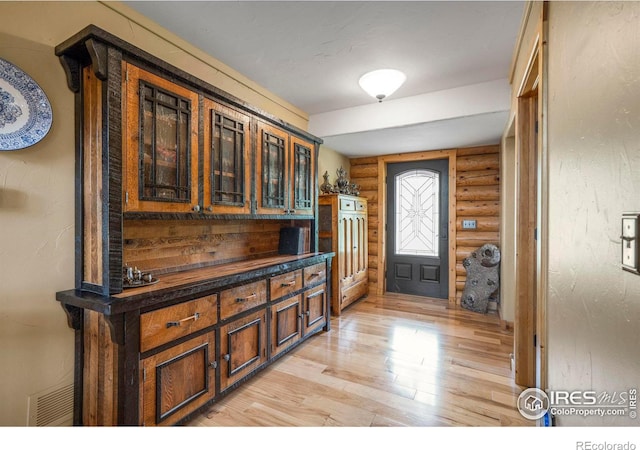 entryway with visible vents, log walls, and light wood-style floors