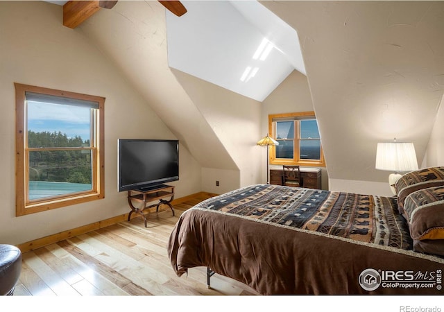 bedroom featuring lofted ceiling with beams, light wood-style flooring, and baseboards