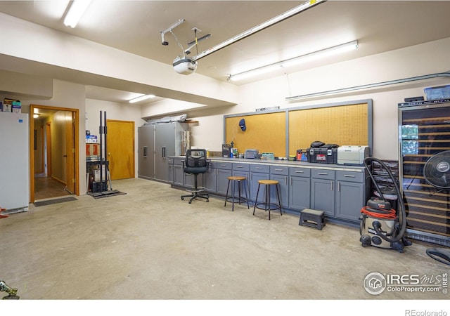 garage with a garage door opener, freestanding refrigerator, and a workshop area