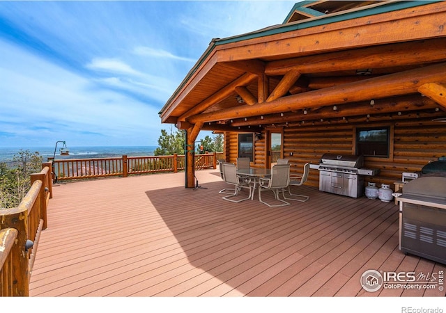 wooden deck with outdoor dining space, a water view, and area for grilling