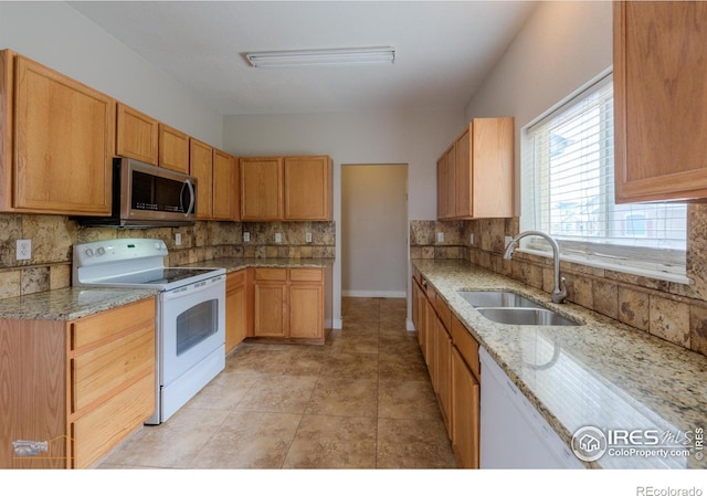 kitchen with white appliances, backsplash, a sink, and light stone counters