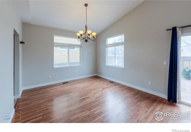 unfurnished room with lofted ceiling, wood finished floors, visible vents, and a notable chandelier