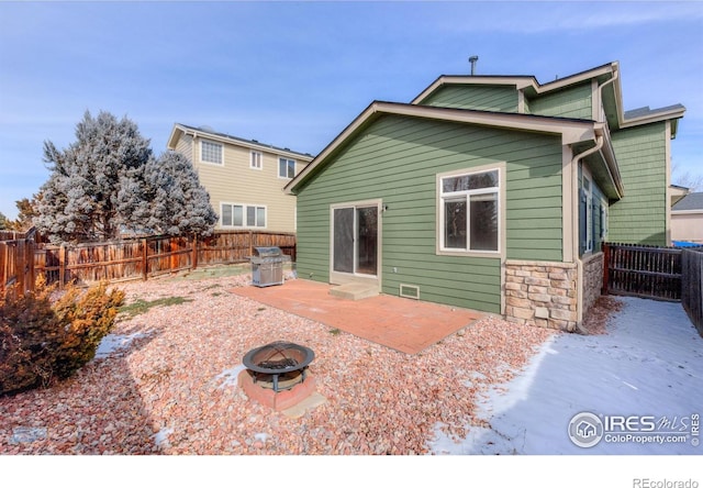 back of house featuring an outdoor fire pit, stone siding, a fenced backyard, and a patio area