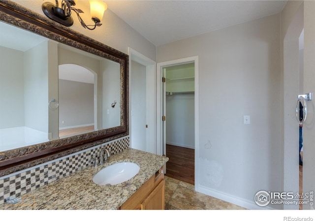 bathroom with baseboards, a spacious closet, and vanity