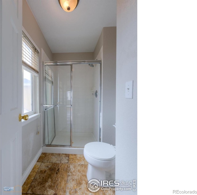 full bathroom featuring a shower stall, toilet, and baseboards