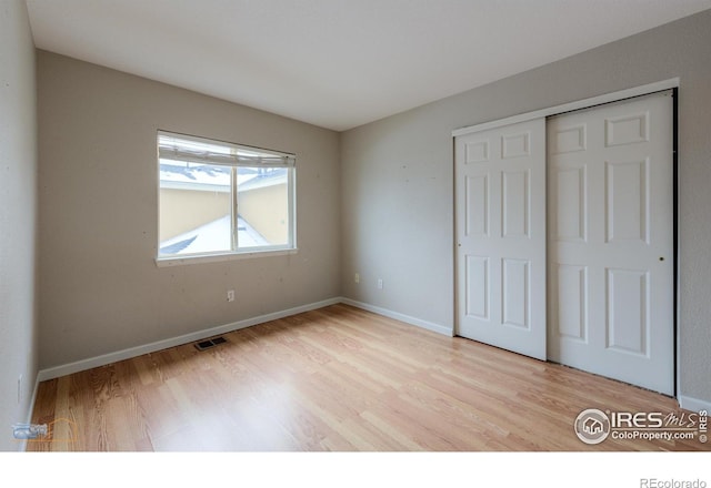 unfurnished bedroom featuring light wood finished floors, a closet, visible vents, and baseboards