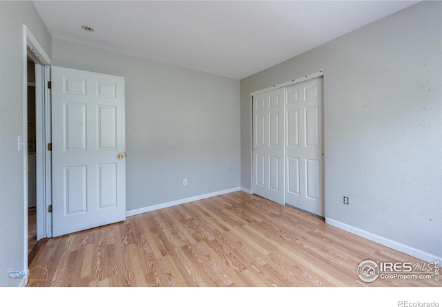 unfurnished bedroom with light wood-style floors, a closet, and baseboards