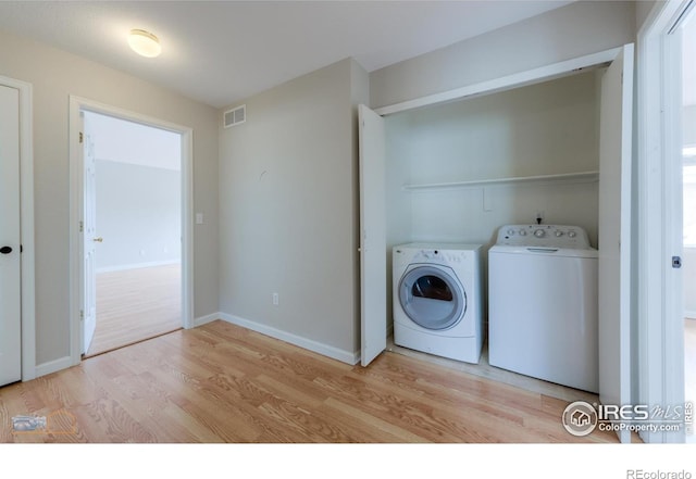 laundry area with laundry area, baseboards, visible vents, light wood-type flooring, and separate washer and dryer