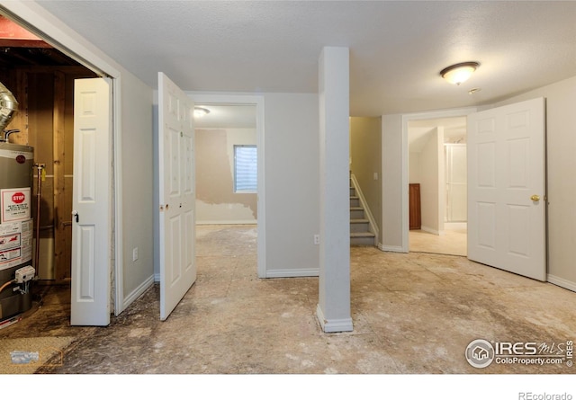 basement with gas water heater, stairway, baseboards, and a textured ceiling