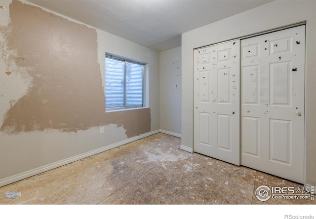 unfurnished bedroom with baseboards and a closet