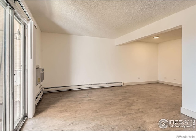 empty room with a healthy amount of sunlight, light wood-style floors, baseboards, and a textured ceiling