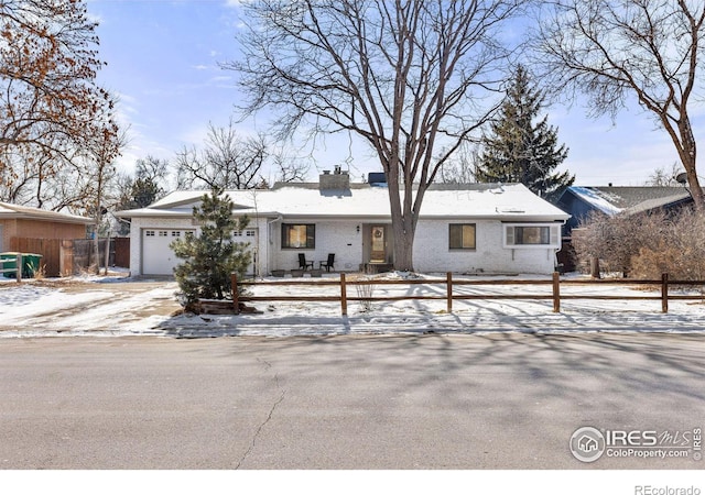 ranch-style house featuring brick siding, fence, a chimney, and an attached garage