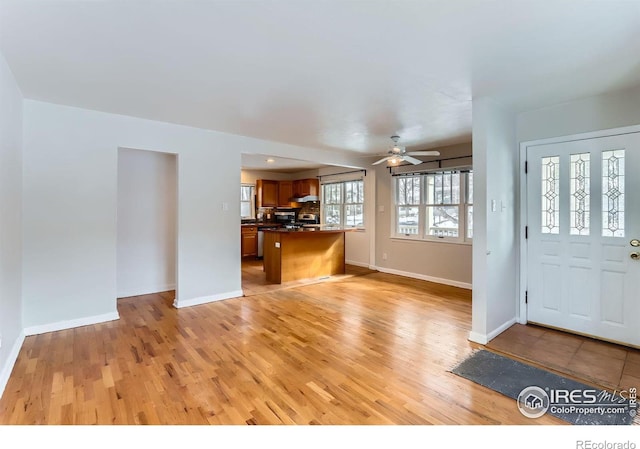 interior space with ceiling fan, baseboards, and light wood-style floors