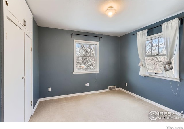 unfurnished bedroom with baseboards, visible vents, and light colored carpet