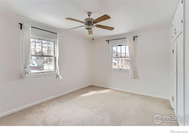 unfurnished bedroom with a ceiling fan, light carpet, and baseboards